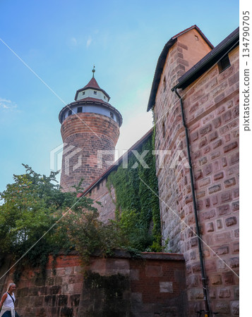 Ancient Stone Tower Rises Over Ivy Covered Wall Under Clear Blue Sky in Nuremberg, Germany 134790705