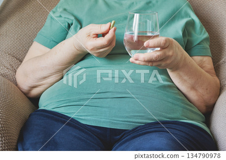 Senior woman taking medication with glass of water for health and wellness Senior woman taking medication with glass of water for health and wellness 134790978