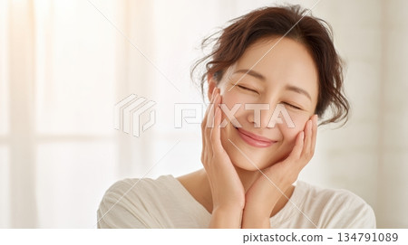 Skin care image of a middle-aged woman smiling with her hands on her cheeks 134791089
