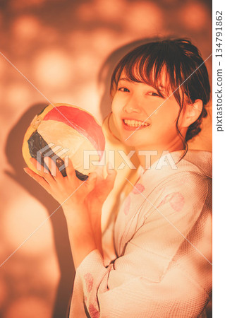 一位身穿和服的年輕女子手持紙氣球。 一位身穿和服的年輕女子手持紙氣球。 134791862