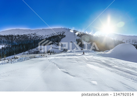 Winter Sun Over Mountain Ski Resort with Groomed Slopes 134792014