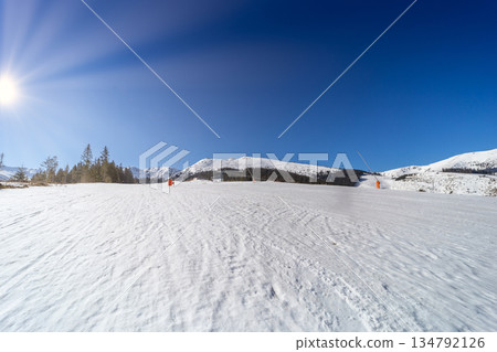 Wide Empty Ski Slope with Sunbeams in Winter Mountains 134792126