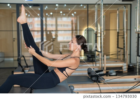 Caucasian woman doing exercises on reformer machine.  134793030