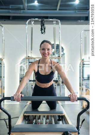 Caucasian woman doing exercises on reformer machine. Caucasian woman doing exercises on reformer machine. 134793058