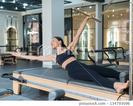 Caucasian woman doing exercises on reformer machine.  134793096