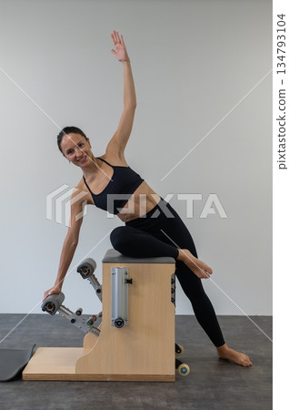 Caucasian woman doing Pilates on classic chair. Caucasian woman doing Pilates on classic chair. 134793104