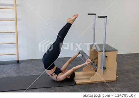 Caucasian woman doing Pilates on classic chair. Caucasian woman doing Pilates on classic chair. 134793107
