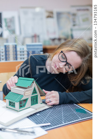 Caucasian young woman making a model of a building. Student of the construction university. Caucasian young woman making a model of a building. Student of the construction university. 134793165