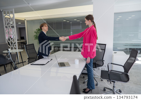 Caucasian man and woman greeting and shaking hands in office. Caucasian man and woman greeting and shaking hands in office. 134793174