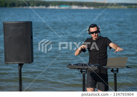 Male DJ playing music on the beach.  134793904