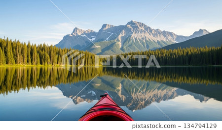 Red kayak on calm lake with reflection of mountain and forest. Outdoor sport, adventure, travel concept for summer vacation. 134794129