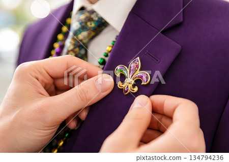 Elegant mardi gras fleur-de-lis brooch on purple blazer suit during festive carnival celebration. concept of new orleans tradition, festive attire, cultural symbolism Elegant mardi gras fleur-de-lis brooch on purple blazer suit during festive carnival celebration. concept of new orleans tradition, festive attire, cultural symbolism 134794236