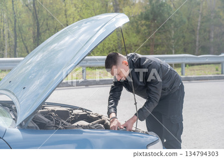 Caucasian man looking under the hood of his car. Caucasian man looking under the hood of his car. 134794303