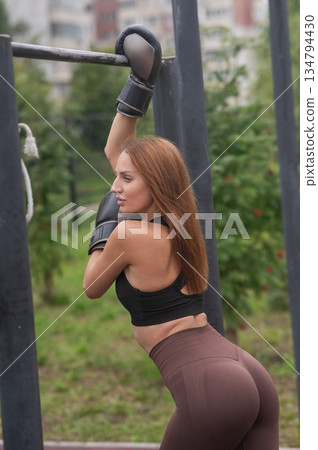 A Caucasian woman poses in boxing gloves on a sports field. A Caucasian woman poses in boxing gloves on a sports field. 134794430