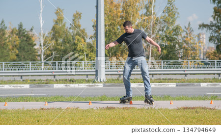 A Caucasian man rollerblades around the slalom course. A Caucasian man rollerblades around the slalom course. 134794649