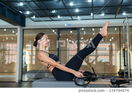 Caucasian woman doing exercises on reformer machine.  134794674