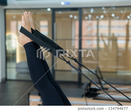 Caucasian woman doing exercises on reformer machine. Caucasian woman doing exercises on reformer machine. 134794677