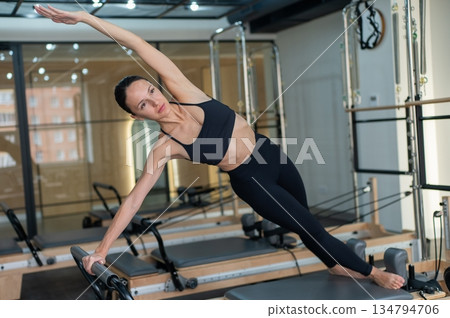 Caucasian woman doing side bends on reformer machine.  134794706