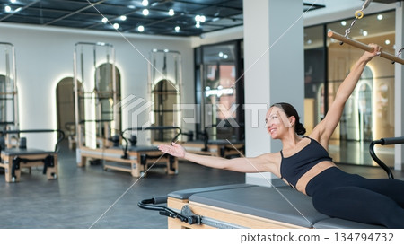 Caucasian woman doing exercises on reformer machine.  134794732