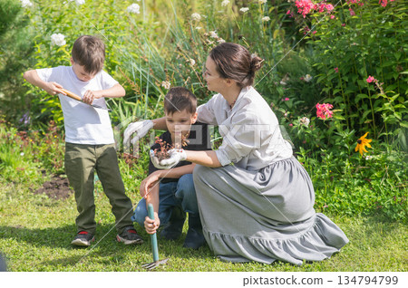 Caucasian woman tending her garden with her sons.  134794799