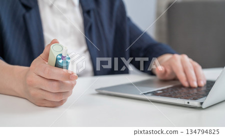 Business woman smoking an electronic cigarette while working on a laptop. Tobacco heating system. Business woman smoking an electronic cigarette while working on a laptop. Tobacco heating system. 134794825
