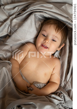 Top view of cute caucasian toddler lying in bed. Top view of cute caucasian toddler lying in bed. 134794901