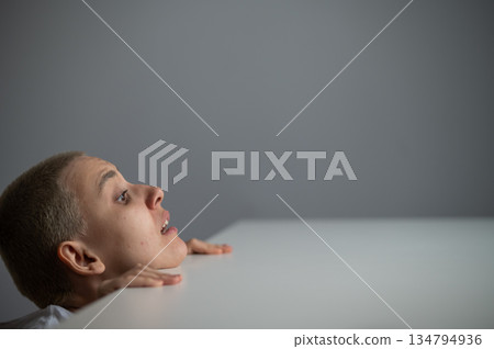 A Caucasian woman with short hair peeks out from under a table. A Caucasian woman with short hair peeks out from under a table. 134794936