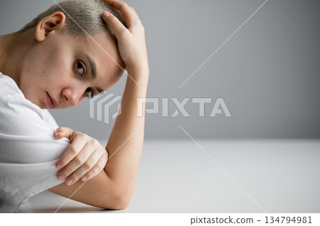Portrait of a sad young woman sitting at a table on a white background. Copy space Portrait of a sad young woman sitting at a table on a white background. Copy space 134794981