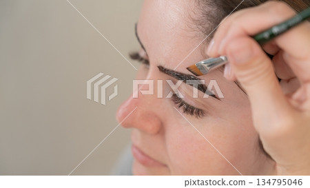 Caucasian woman getting eyebrow tinting procedure. Caucasian woman getting eyebrow tinting procedure. 134795046