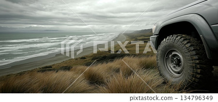 Family SUV Parked on Scenic Beach Road Overlooking Ocean with Waves and Dramatic Clouds 134796349