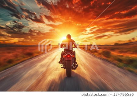Motorcyclist Speeding Down An Open Road At Sunset With Dramatic Cloudy Sky 134796586