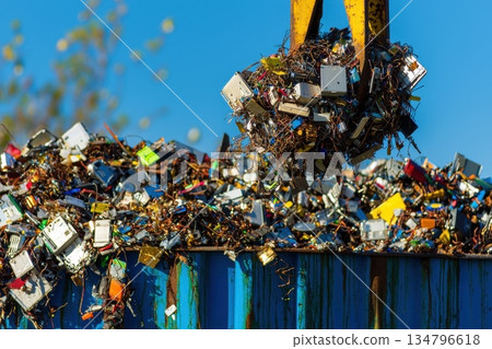 Industrial Magnet Lifting Discarded Metal Waste in a Recycling Yard Under Clear Blue Sky Industrial Magnet Lifting Discarded Metal Waste in a Recycling Yard Under Clear Blue Sky 134796618