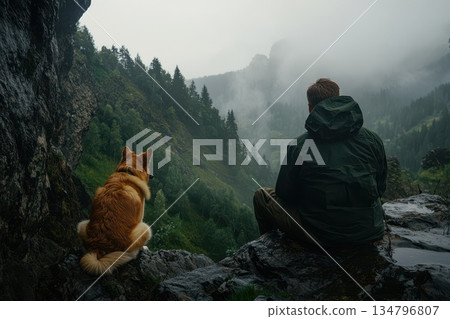 Man and his loyal German shepherd sitting on rock in misty mountain landscape 134796807