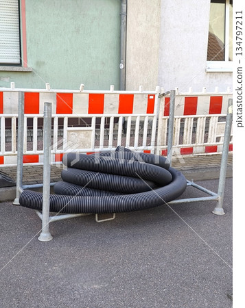 A coiled piece of corrugated pipe for cable or drainage enclosed by a construction barrier A coiled piece of corrugated pipe for cable or drainage enclosed by a construction barrier 134797211