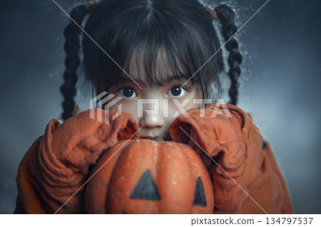Girl wearing an orange sweater holding a pumpkin 134797537