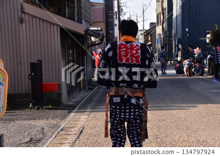 Inuyama City, Aichi Prefecture, Japan: A man participating in the spring Inuyama Festival, wearing a happi coat and walking down an alleyway, in a residential area around Inuyama Castle 134797924