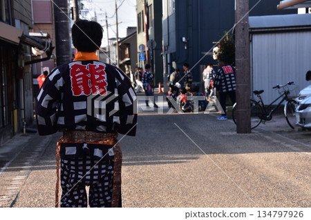 Inuyama City, Aichi Prefecture, Japan: A man participating in the spring Inuyama Festival, wearing a happi coat and walking down an alleyway, in a residential area around Inuyama Castle 134797926