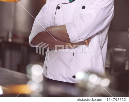 professional chef stands and working in a modern kitchen, wearing a white uniform. This image conveys expertise, focus, and readiness in a high demand culinary environment for restaurant profile professional chef stands and working in a modern kitchen, wearing a white uniform. This image conveys expertise, focus, and readiness in a high demand culinary environment for restaurant profile 134798552