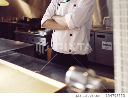 professional chef stands and working in a modern kitchen, wearing a white uniform. This image conveys expertise, focus, and readiness in a high demand culinary environment for restaurant profile professional chef stands and working in a modern kitchen, wearing a white uniform. This image conveys expertise, focus, and readiness in a high demand culinary environment for restaurant profile 134798553