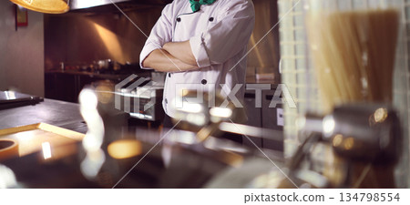 professional chef stands and working in a modern kitchen, wearing a white uniform. This image conveys expertise, focus, and readiness in a high demand culinary environment for restaurant profile professional chef stands and working in a modern kitchen, wearing a white uniform. This image conveys expertise, focus, and readiness in a high demand culinary environment for restaurant profile 134798554