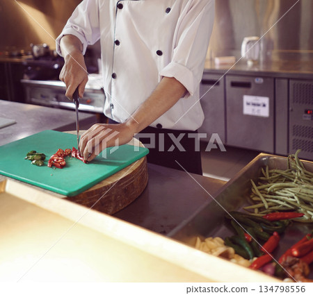 professional chef stands and working in a modern kitchen, wearing a white uniform. This image conveys expertise, focus, and readiness in a high demand culinary environment for restaurant profile professional chef stands and working in a modern kitchen, wearing a white uniform. This image conveys expertise, focus, and readiness in a high demand culinary environment for restaurant profile 134798556