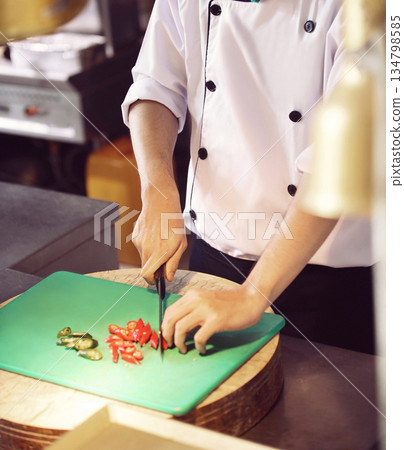 professional chef stands and working in a modern kitchen, wearing a white uniform. This image conveys expertise, focus, and readiness in a high demand culinary environment for restaurant profile professional chef stands and working in a modern kitchen, wearing a white uniform. This image conveys expertise, focus, and readiness in a high demand culinary environment for restaurant profile 134798585