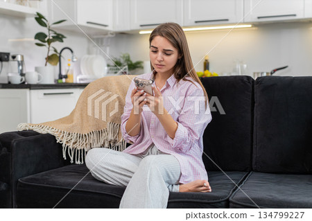 Young woman upset by game loss and job refusal sighs touches brow shakes head no holding smartphone Young woman upset by game loss and job refusal sighs touches brow shakes head no holding smartphone 134799227