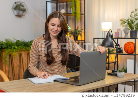 Young woman powers up laptop starts focused work on morning tasks and keeps calm early rhythm inside Young woman powers up laptop starts focused work on morning tasks and keeps calm early rhythm inside 134799239