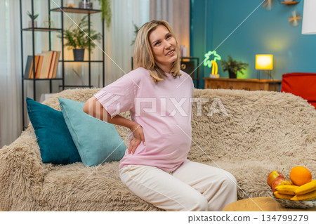 Pregnant woman holding sore lower back pain showing strong discomfort spine strain during pregnancy 134799279