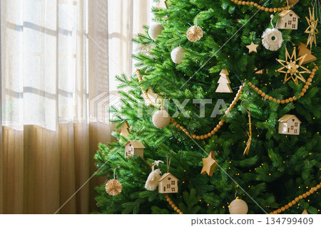Festive Christmas Tree with natural wooden ornaments and garland with wrapped holiday gifts boxes Festive Christmas Tree with natural wooden ornaments and garland with wrapped holiday gifts boxes 134799409