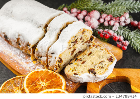 Traditional sliced Christmas stollen loaf with raisins and powdered sugar on wooden cutting board Traditional sliced Christmas stollen loaf with raisins and powdered sugar on wooden cutting board 134799414
