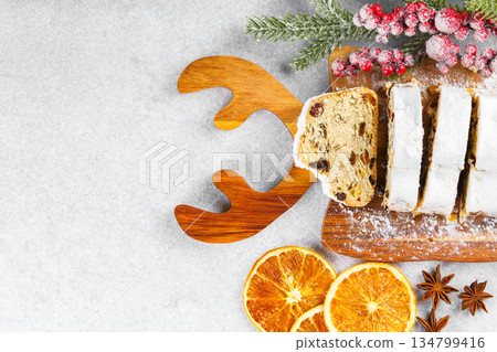 Traditional sliced Christmas stollen loaf with raisins and powdered sugar on wooden cutting board 134799416