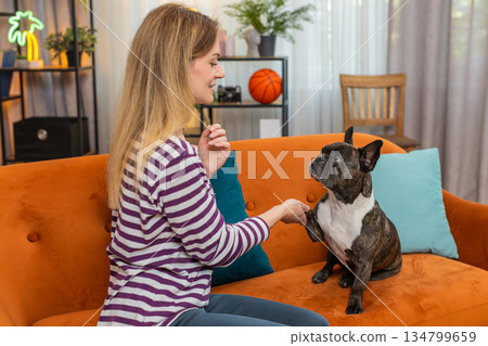 Middle-aged woman with dog trains give paw trick laughs and rewards with praise on smartphone video 134799659