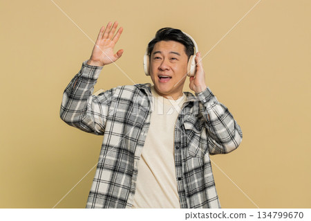 Happy Asian man listening music on headphones and dancing disco fooling around having fun 134799670